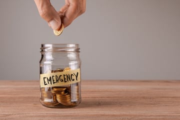 Man putting coin into jar labeled emergency