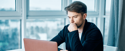 man looking at his laptop and thinking