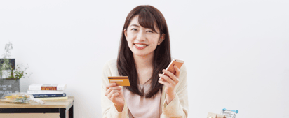 woman holding a credit card and a phone and smiling