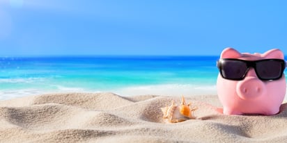 Piggy bank on the beach wearing sunglasses