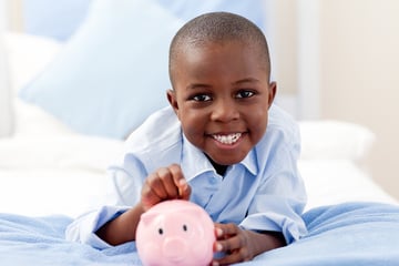Young boy saving money in a piggy bank