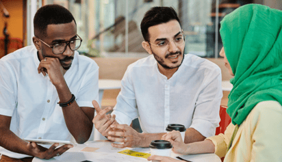 two men talking to a lady wearing a hijab