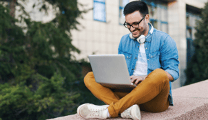 man wearing glasses sitting and typing on his laptop