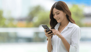 asian woman looking at her phone and smiling