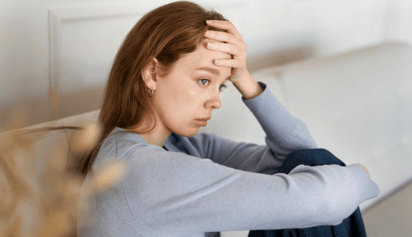 woman with a hand on her head is feeling anxious