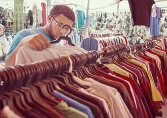 Young man purchasing second hand clothing