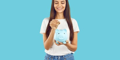 young woman putting coin into a piggy bank.