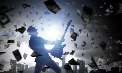 Man playing an electric guitar wearing a hat with dollar bills floating all around him singing songs about money