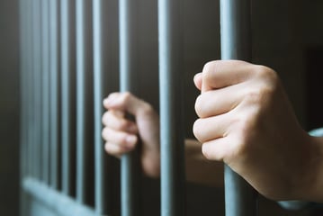 Person in jail with hands on bars for failure to pay child support 